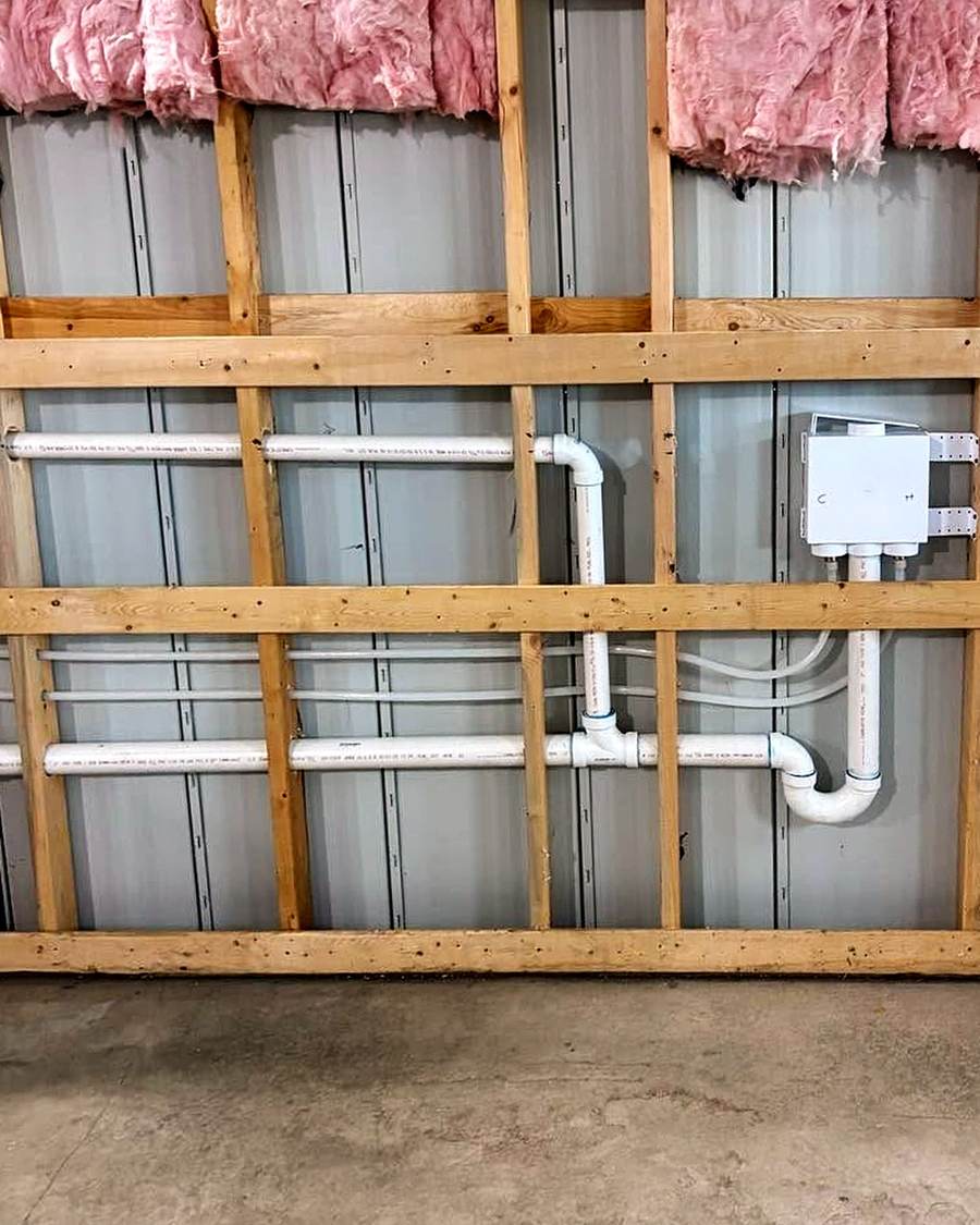 White plastic water lines and a drain roughed in for a laundry hookup