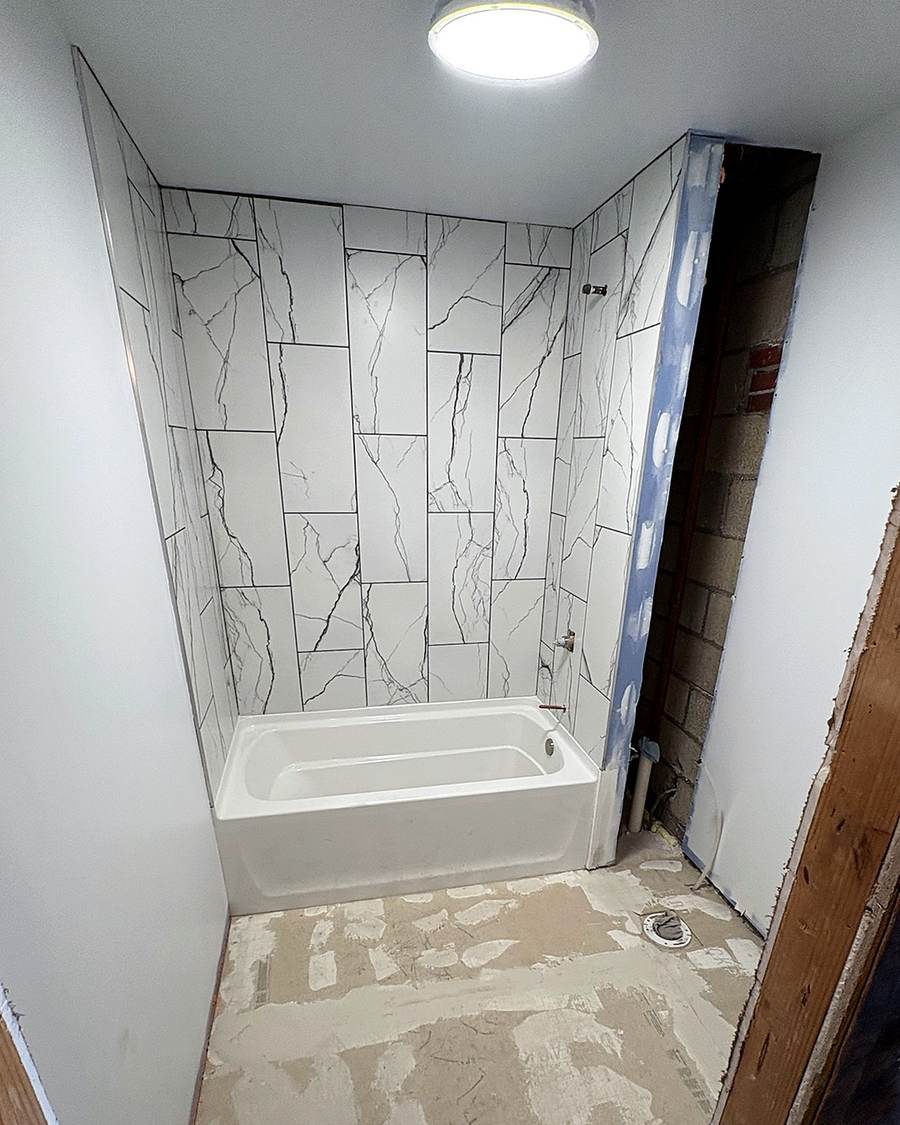 Finished white tile on a tub surround in a Leesburg apartment bathroom