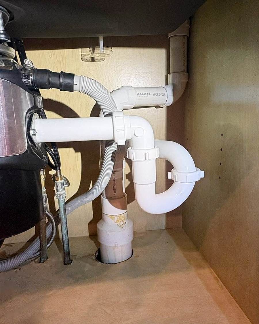 New plastic kitchen drain and braided supply lines under a sink in South Bend